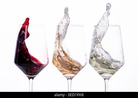 Red, rosé, and white wine splash in three clear glasses. Stock Photo