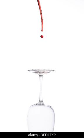 Liquid falls into an empty glass in a studio setting Stock Photo