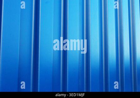Full frame texture of blue corrugated metal siding with vertical lines and shadows. Stock Photo
