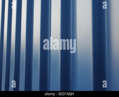 Perspective view of a blue corrugated metal wall showing rhythmic vertical ridges and metallic shine. Stock Photo