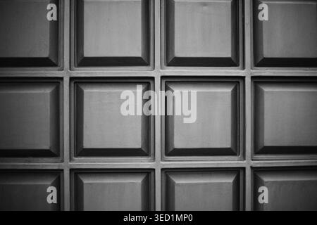 Full frame of a dark gray metal or plastic panel with a repeating square geometric pattern. Stock Photo