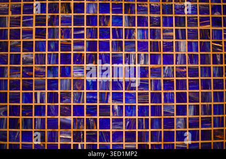 Texture of small square mosaic tiles in various shades of deep blue with beige grout. Stock Photo