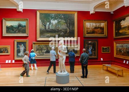 Visitors viewing oil paintings and a marble statue in a Victorian gallery at Leeds Art Gallery, West Yorkshire, England, UK Stock Photo