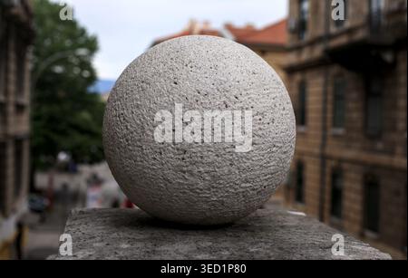 Stone sphere decorative element on a building balcony in Rijeka city center, Croatia. Close-up of rough texture with blurred urban background. Stock Photo