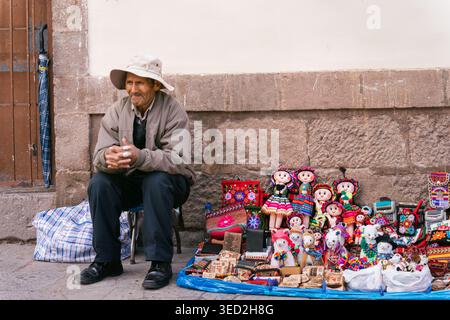 Cusco, Peru - March 23, 2025: An elderly Peruvian man selling handmade crafts souvenirs outside the San Pedro Market Stock Photo