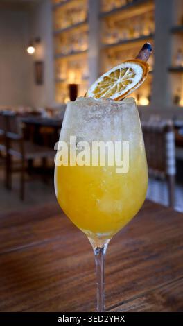 Refreshing craft orange cocktail served in a stemmed glass with crushed ice. The artisanal drink is garnished with a dehydrated citrus wheel and a smo Stock Photo