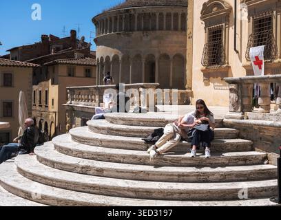 Young couple sitting on the steps in Piazza Grande in Arezzo Tuscany Italy Stock Photo