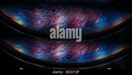Oil fluid. Gasoline leak. Defocused blue yellow purple color round bubble liquid paint blend wave floating on abstract dark black background Stock Photo