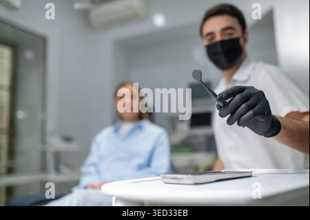 Dentist hands in black gloves holding tools Stock Photo