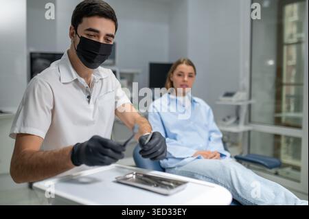 Dentist hands in black gloves with tools Stock Photo