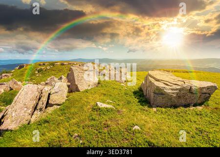 sunset over mountainous landscape during summertime. boulders and rock formations surrounded grassy hills. picture of an untouched highland. leadershi Stock Photo