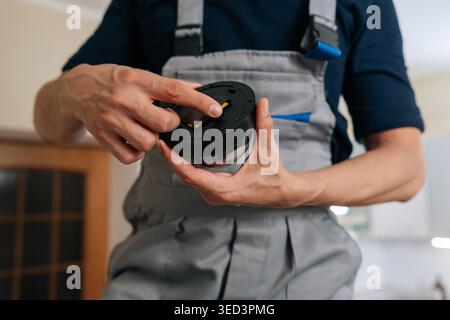 Close-up of male technician in uniform holding dome surveillance camera. Professional worker installs smart home security system for safety and Stock Photo