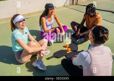 Diverse young adults enjoying a pickleball break outdoors Stock Photo