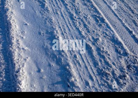 Snow texture with tire tracks on icy winter road surface Stock Photo