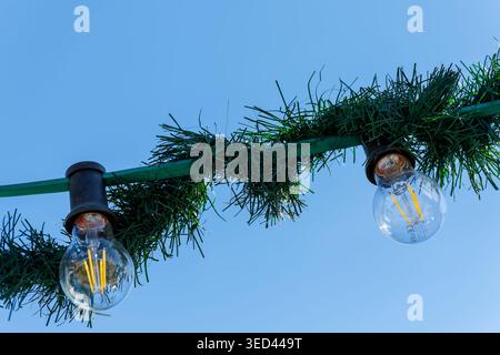 LED light bulbs strung on a green garland against a clear blue sky Stock Photo
