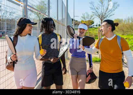 Diverse friends walking and laughing after playing pickleball Stock Photo