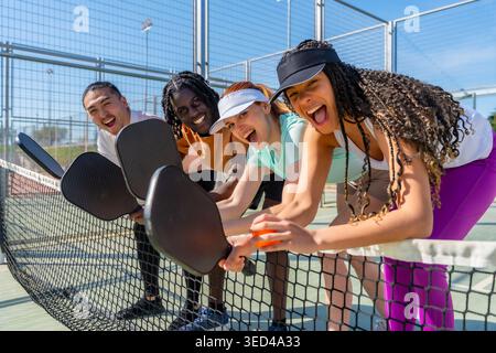 Diverse friends enjoying pickleball game on court Stock Photo