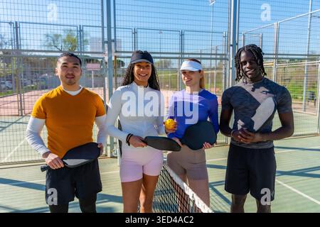 Diverse friends enjoying pickleball on outdoor court Stock Photo