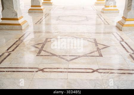 Mosque marble floor with geometric inlay pattern featuring eight pointed star motif between column bases in open courtyard. Islamic architecture, deco Stock Photo