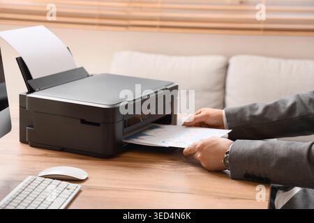 Male hands using printer on desk in office Stock Photo
