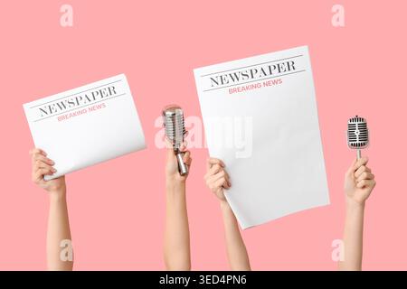 Female hands with newspapers and microphones on pink background Stock Photo