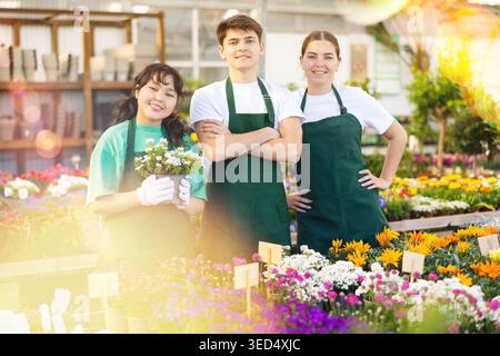 Group portrait of three young skilled botanists smiling at camera in greenhouse Stock Photo
