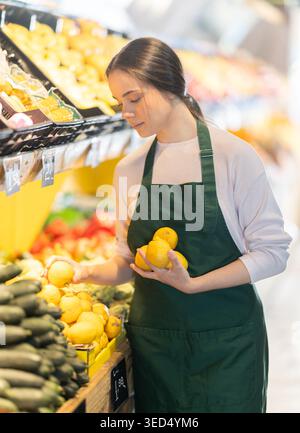 woman seller puts lemons on the counter, she puts them on the shelf Stock Photo
