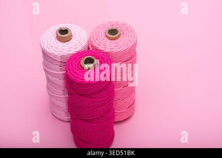 Three spools of thread in various shades of pink, arranged on a light pink background. Stock Photo