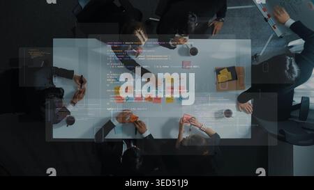 A group of professionals in formal attire engages in a collaborative meeting, utilizing brainstorming tools and coding while strategizing over project Stock Photo