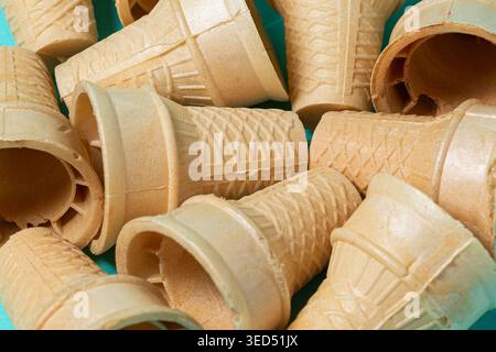 A close-up image of several waffle ice cream cones piled together on a blue surface. Stock Photo