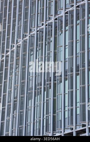 Abstract view of a contemporary building exterior featuring vertical metallic pipes and rectangular wire mesh panels. The repetitive industrial patter Stock Photo