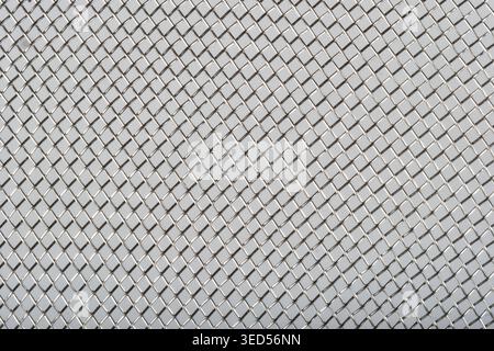 high angle shot shows a detailed silver stainless steel woven wire mesh screen with a repeating diagonal square pattern. Stock Photo