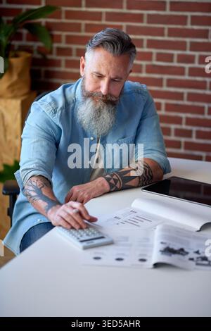 Businessman, accountant and documents with calculator for financial planning or audit in office. Mature, man or accounting with paperwork or Stock Photo