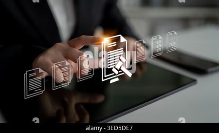 A business professional interacts with a digital tablet displaying document icons, symbolizing the intersection of technology and law in a modern Stock Photo