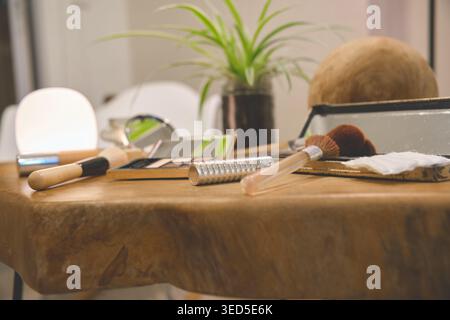 Makeup brushes, eyeshadow palette, and skincare items arranged on a natural wood surface Stock Photo
