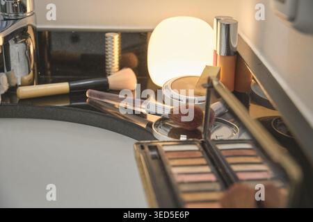 Makeup brushes and beauty products sitting on a dark bathroom counter Stock Photo