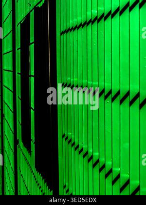 Abstract perspective of a vibrant green metal industrial shutter or siding, showcasing clean vertical lines and dark geometric shadows in Brazil. Stock Photo