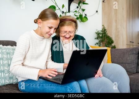 Granddaughter and grandmother making videocall with family. Stock Photo