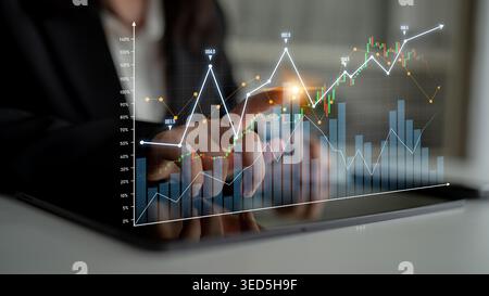A business professional interacts with a tablet displaying advanced graphs and charts that signify financial growth and analytics in a corporate Stock Photo