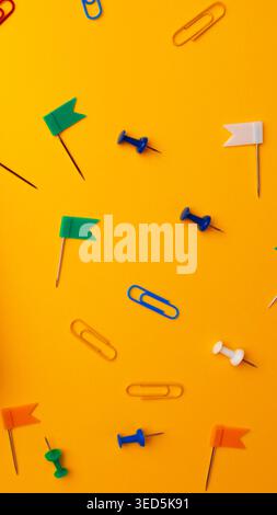 Colorful stationery items scattered on a bright yellow surface during daylight hours Stock Photo