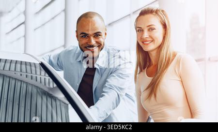 Two people in a car dealership discussing vehicle options during daytime Stock Photo