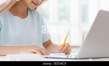 Student writes notes while studying at home during daytime Stock Photo