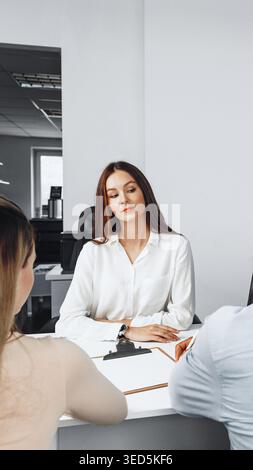 Business meeting takes place in modern office with three professionals discussing tasks Stock Photo