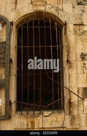 ​Ancient stone window archway with rusted iron bars on a traditional limestone building, Jounieh, Lebanon. Stock Photo