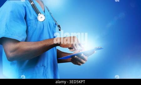 Medical professional checks patient data on a tablet in a blue environment Stock Photo