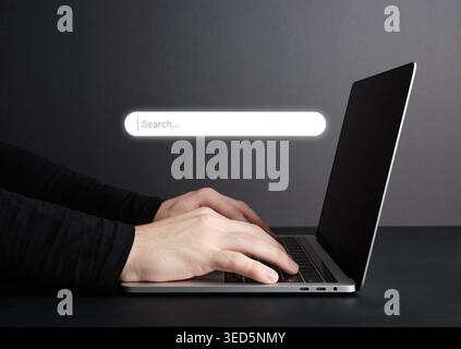 Hands typing on laptop keyboard with search bar hologram, concept of internet browsing and online business Stock Photo