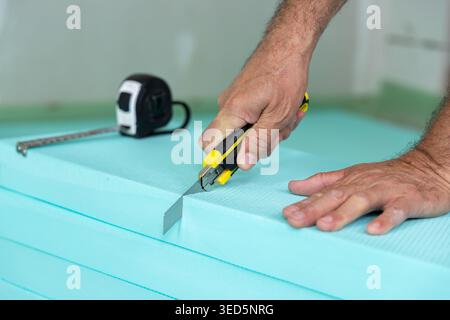 Construction worker cutting insulation boards before laying and fixing on a construction site Stock Photo
