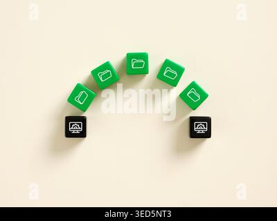 Green dice showing folder icons transferring data to black dice showing computer processing icon representing file sharing and data transfer Stock Photo