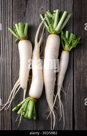 Minimal composition of daikon radish on wooden background, white radish, healthy food concept Stock Photo