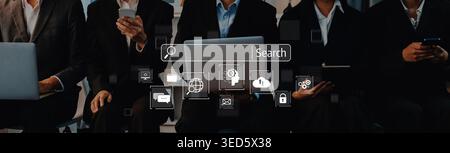 Business professionals are focused on their devices, surrounded by digital icons representing communication and search, symbolizing modern workplace Stock Photo